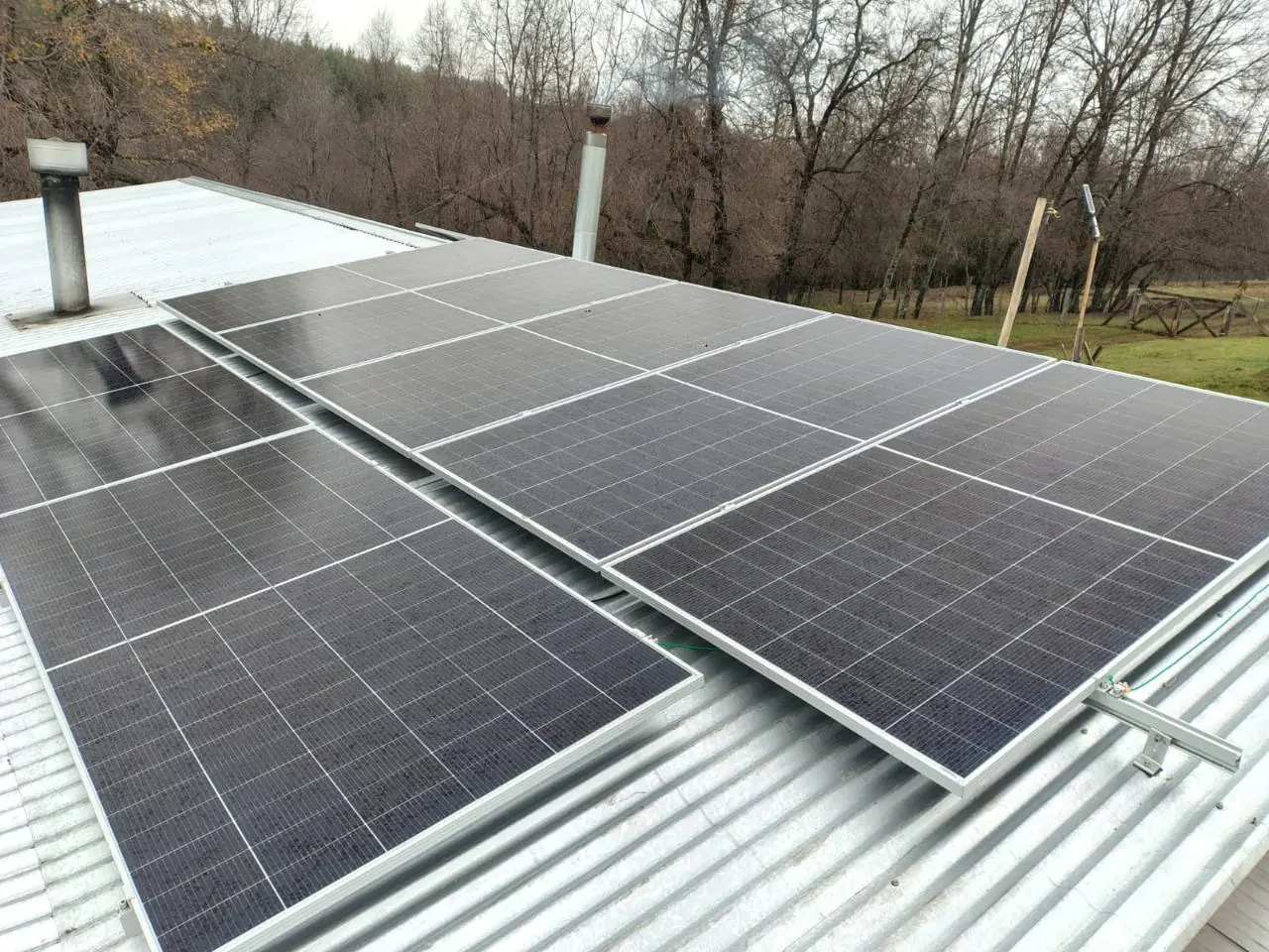 Paneles solares instalados por Sol Reflect sobre techo de zinc en Antuco, con bosque al fondo